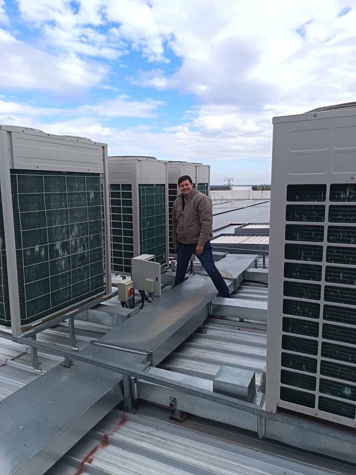 Technician on rooftop between commercial HVAC units